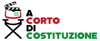 Logo tipografico “A corto di Costituzione” con la parola “CORTO” in rosso e “COSTITUZIONE” in verde su sfondo nero, accompagnato da un elemento grafico che richiama un libro aperto, a rappresentare il legame tra cinema e educazione civica.